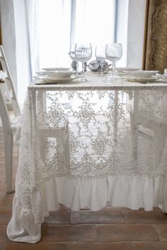 the table is set with white linens and place settings for two people to sit at