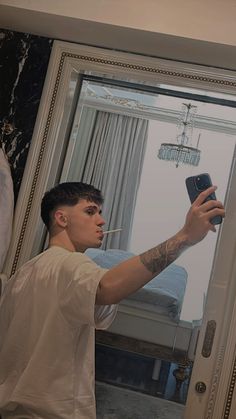 a young man taking a selfie in front of a mirror with his cell phone