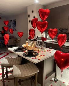 red heart balloons floating in the air over a kitchen table with candles and plates on it