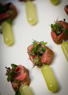 several small appetizers are arranged on a white plate with green garnishes