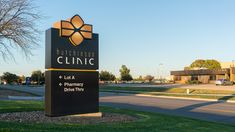 a black and gold sign sitting in the middle of a grass covered field next to a road