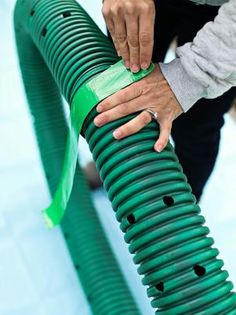 a person holding onto a green hose with their hand on it's end,