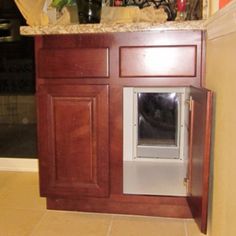 a dog door is open in the corner of a kitchen with cabinets and counter tops