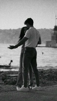 black and white photograph of two people standing near water