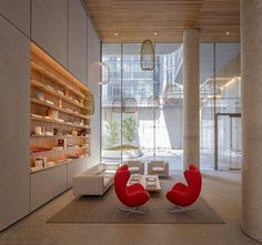 a living room filled with lots of furniture next to tall columns and glass windows on the wall