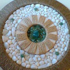 a decorative wall hanging made out of rocks and glass pebbles with a green center piece in the middle