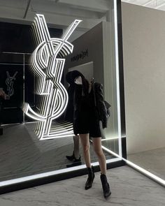 a woman standing in front of a large window with a dollar sign on it's side