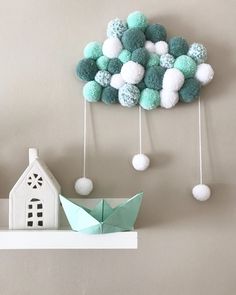 an origami boat and some balls are hanging from the wall next to a paper house