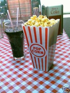 a red and white checkered table with a cup of popcorn