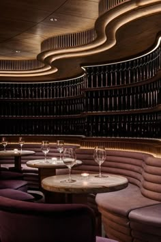 the interior of a restaurant with round tables and purple velvet chairs, along with wine glasses