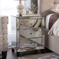 a mirrored night stand with two drawers and a lamp on it's end table