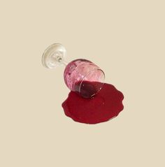 a bottle of wine sitting on top of a table next to a red liquid puddle