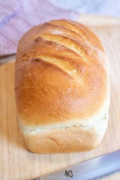 a loaf of bread sitting on top of a wooden cutting board next to a knife