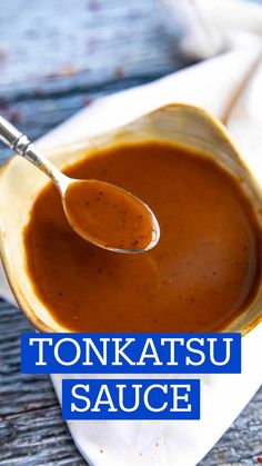 a spoon full of sauce sitting on top of a white plate with the words tonkatsu sauce