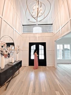 a woman in a long pink dress is standing in the middle of a large room