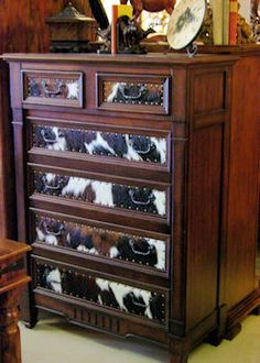 a brown and white cow print chest of drawers in a room with mirrors on the wall