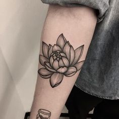 a black and white photo of a lotus flower on the left inner arm, with a jar in front of it