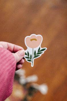 a person holding a flower sticker in their hand