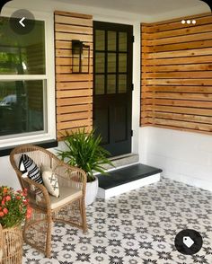 two wicker chairs sitting on a porch next to a potted plant and door