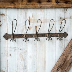 an old metal rack with five pairs of scissors hanging from it's side on a white wooden wall