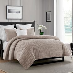 a bedroom with a bed, chair and pictures on the wall above it that is decorated in neutral colors