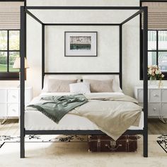 a bedroom with four poster bed and white walls