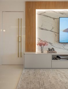 a flat screen tv mounted to the side of a wall next to a vase with flowers