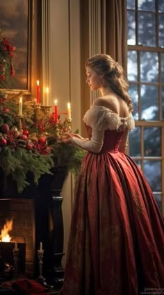 a woman in a long red dress standing next to a christmas tree with lit candles