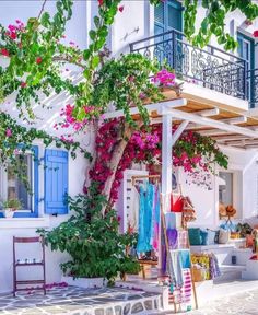 a white house with blue shutters and pink flowers