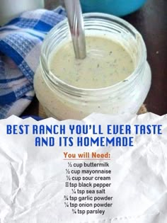 a jar filled with homemade ranch dressing sitting on top of a wooden table next to a blue and white towel