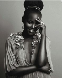 a black and white photo of a woman in a dress holding her hand up to her face