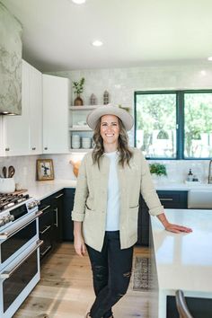 a woman wearing a hat standing in a kitchen