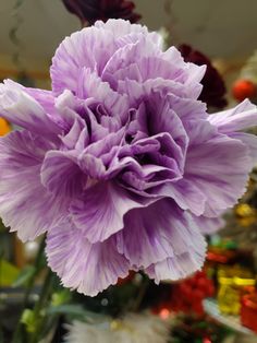 a large purple flower is in the middle of a room with other flowers and decorations