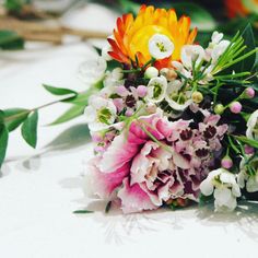 a bouquet of flowers sitting on top of a white countertop next to green leaves