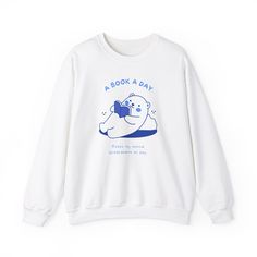 a white sweatshirt with an image of a polar bear reading a book on the front