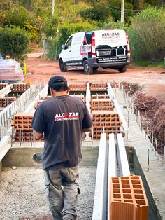 a man walking down a road next to lots of wooden pallets on the ground