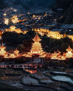 an aerial view of a city lit up at night with lights on buildings and trees in the foreground