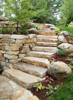 stone steps leading up to the top of a hill with flowers and trees in the background