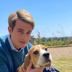 a man holding a brown and white dog on top of a grass covered park bench