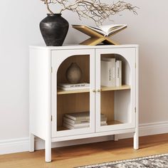 a white cabinet with books and a vase on top