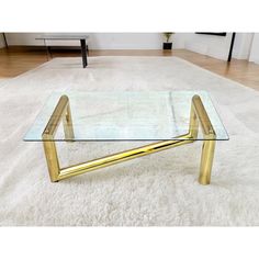 a glass and gold coffee table on a white rug