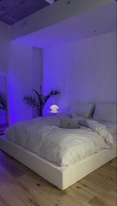 a white bed sitting in a bedroom next to a blue light on the wall above it