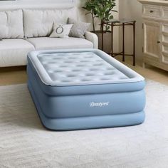 an inflatable mattress sitting on the floor next to a couch