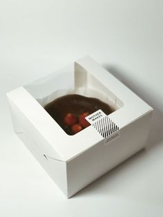 a white box filled with chocolate cake and strawberries in it's bottom half