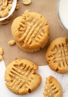 three peanut butter cookies sitting on top of a counter next to a glass of milk