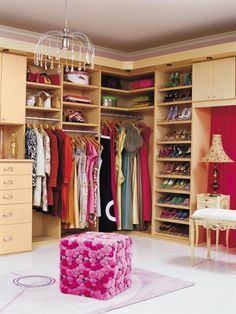 an organized closet with clothes and shoes on the shelves, chandelier hanging from the ceiling