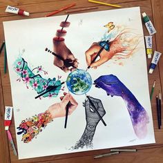 several different colored pencils and markers on a table next to an art work with hands holding the earth