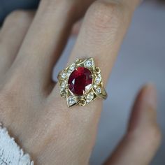 a woman's hand with a ring on it and a red stone in the middle