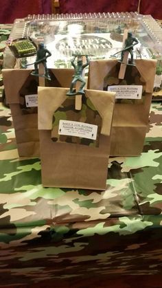 three brown bags sitting on top of a table covered in green and camo paper