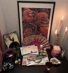 a black table topped with lots of items next to a lit candle and framed art